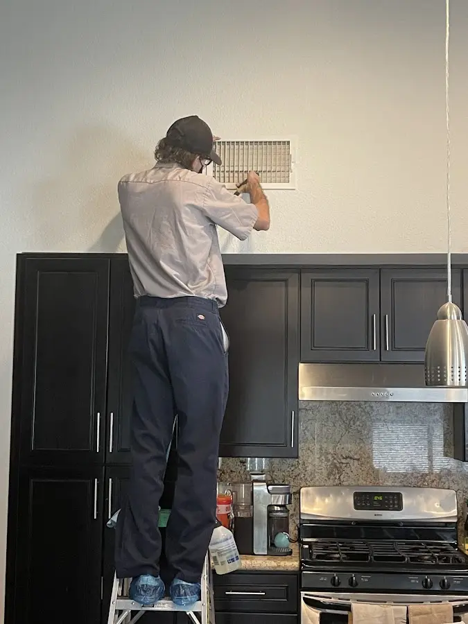 Technician inspecting an air vent during HVAC service in Doffing